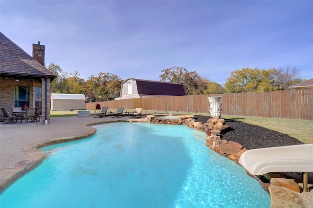 view of pool with an in ground hot tub, a water slide, and a patio