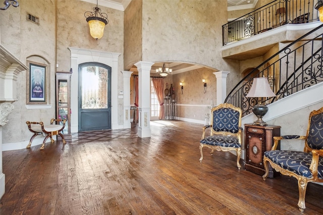 foyer featuring ornate columns, ornamental molding, and hardwood / wood-style floors