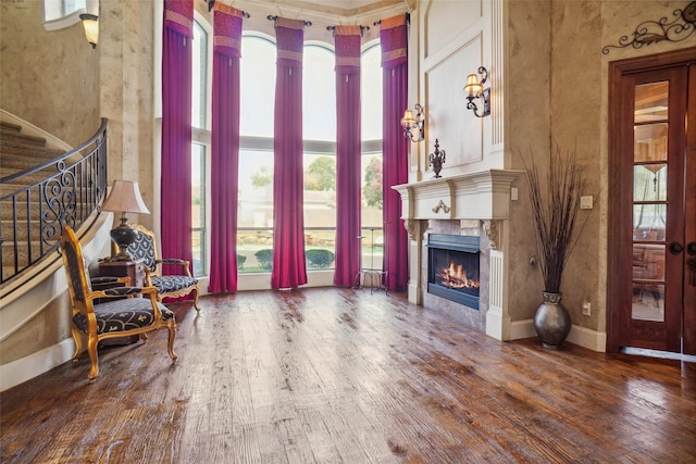 living room with hardwood / wood-style flooring, a tile fireplace, and a high ceiling