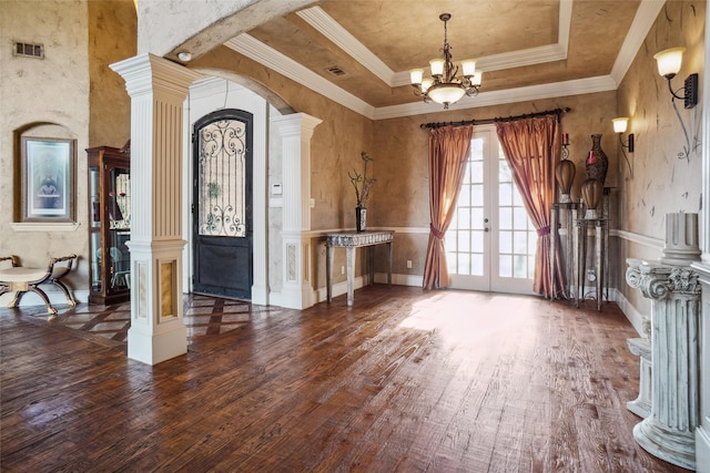 entrance foyer featuring decorative columns, a raised ceiling, dark hardwood / wood-style flooring, french doors, and a chandelier