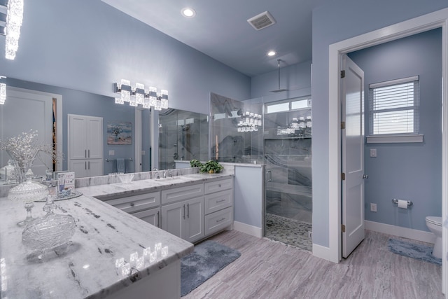 bathroom with toilet, a shower with door, and vanity