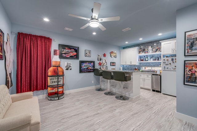 bar featuring white fridge, light hardwood / wood-style floors, backsplash, and white cabinets