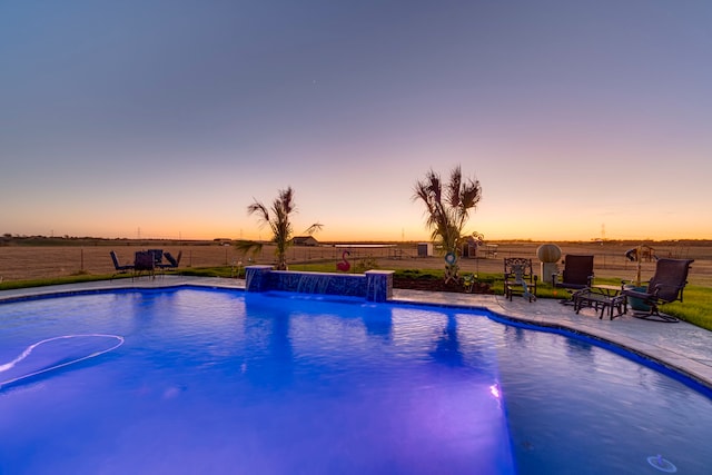 pool at dusk featuring a patio area and pool water feature