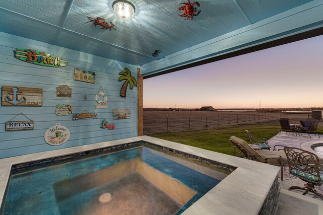 pool at dusk with pool water feature, a shed, and a patio area