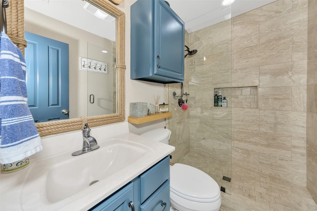 bathroom with a tile shower, vanity, and toilet