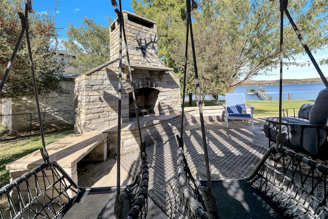 view of patio / terrace featuring an outdoor stone fireplace and a water view