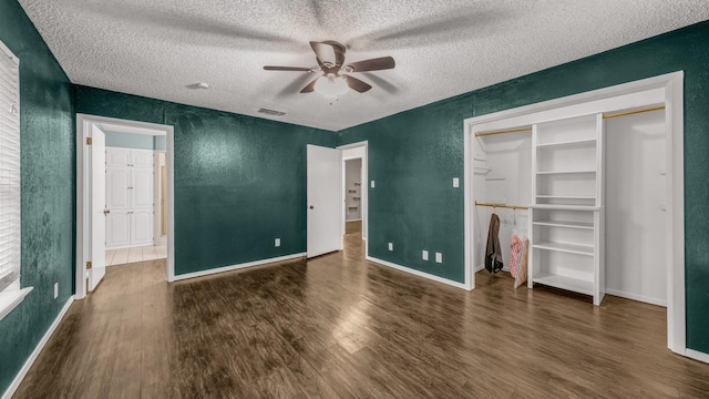 unfurnished bedroom with ceiling fan, a closet, dark wood-type flooring, and a textured ceiling