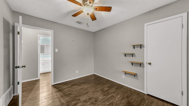 unfurnished bedroom with a textured ceiling, dark hardwood / wood-style flooring, and ceiling fan