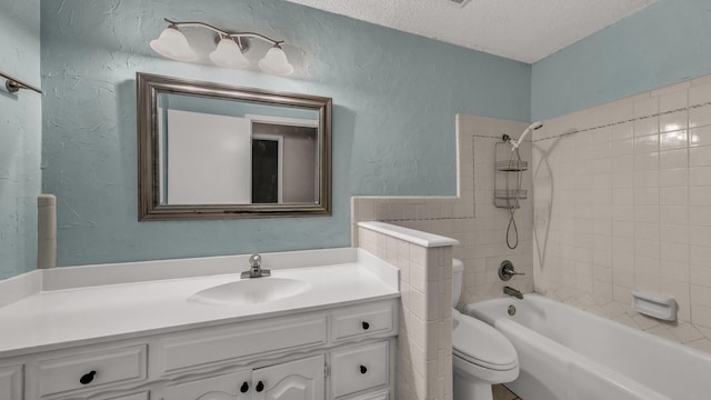 full bathroom featuring vanity, toilet, a textured ceiling, and tiled shower / bath