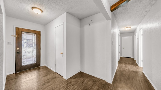 entrance foyer featuring beamed ceiling, dark hardwood / wood-style floors, and a textured ceiling