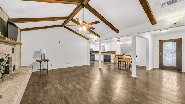 living room with ceiling fan, vaulted ceiling with beams, dark hardwood / wood-style flooring, a textured ceiling, and a fireplace