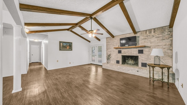 unfurnished living room with vaulted ceiling with beams, a textured ceiling, a fireplace, dark hardwood / wood-style flooring, and decorative columns