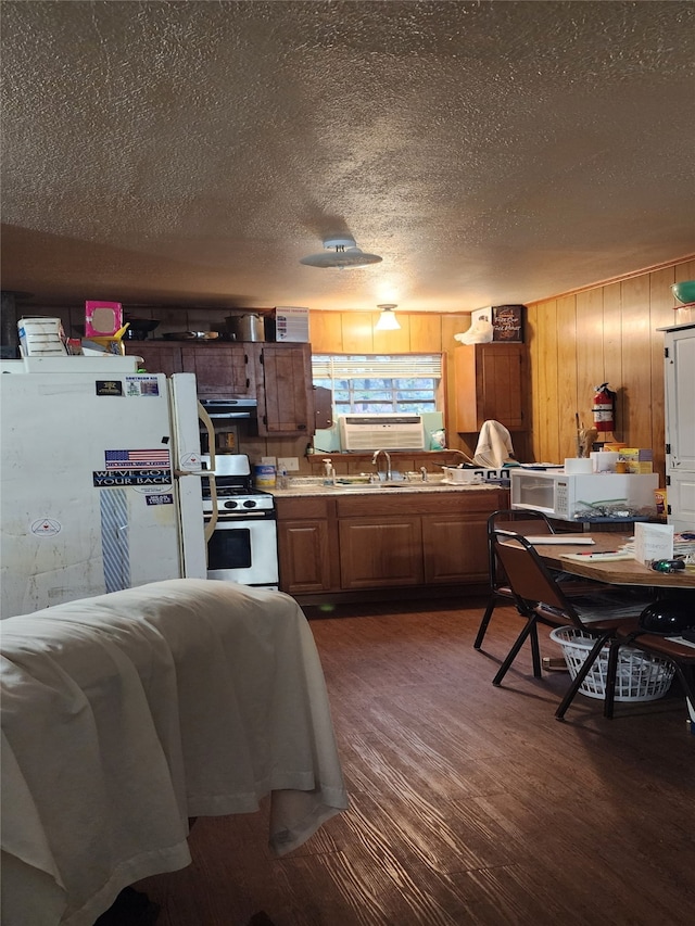 kitchen featuring gas range, a textured ceiling, dark hardwood / wood-style floors, white fridge, and range hood