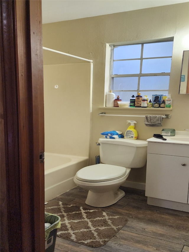 full bathroom featuring hardwood / wood-style flooring, washtub / shower combination, vanity, and toilet