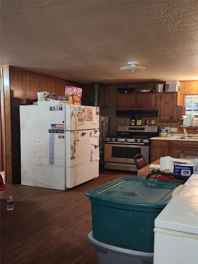 kitchen featuring dark wood-type flooring, sink, a textured ceiling, white fridge, and stainless steel range oven