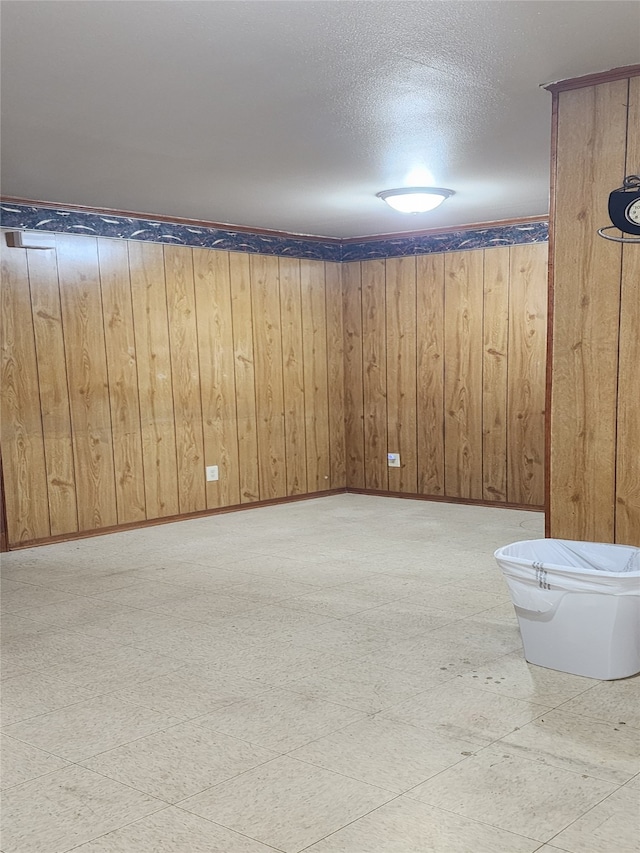 basement featuring a textured ceiling and wood walls