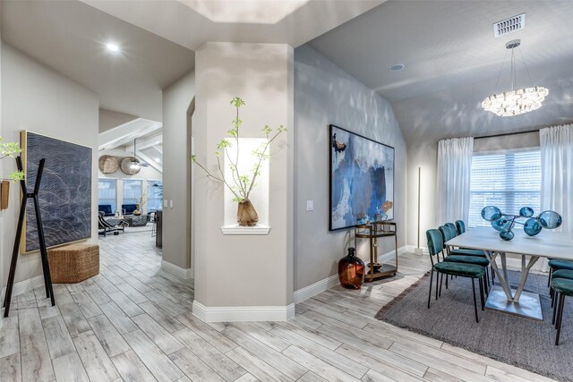 interior space with a chandelier, vaulted ceiling, and light wood-type flooring