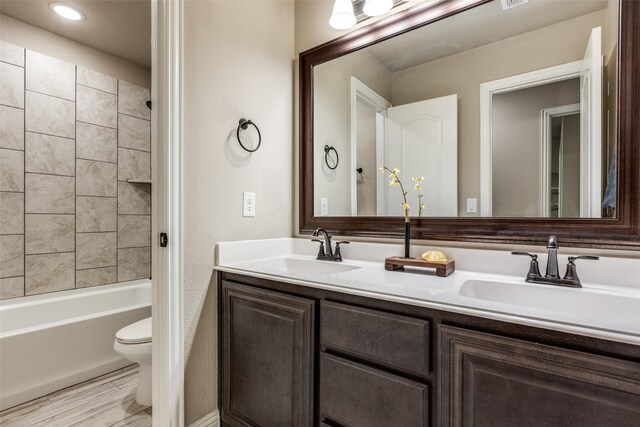 full bathroom with hardwood / wood-style floors, vanity, toilet, and tiled shower / bath