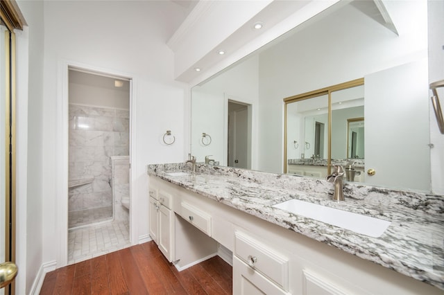 bathroom with a tile shower, toilet, vanity, and hardwood / wood-style flooring