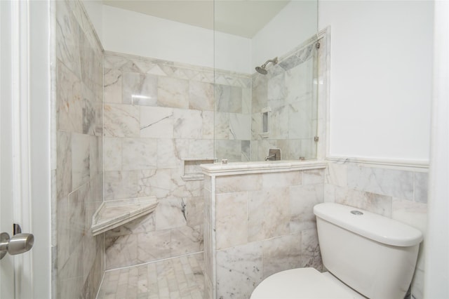 bathroom with tiled shower, toilet, and tile walls