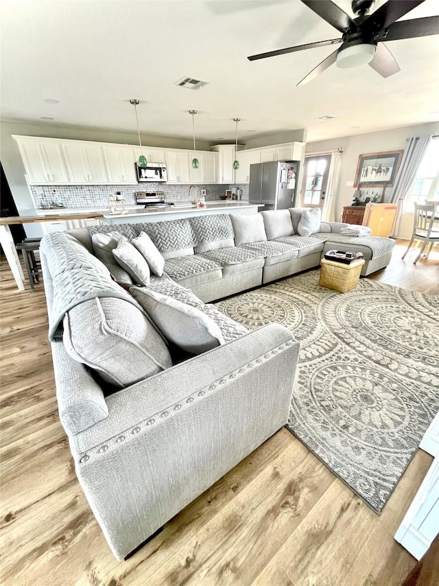 living room featuring ceiling fan, sink, and light hardwood / wood-style floors