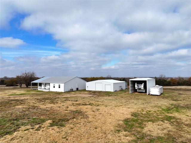 view of yard featuring a carport, a garage, and an outdoor structure