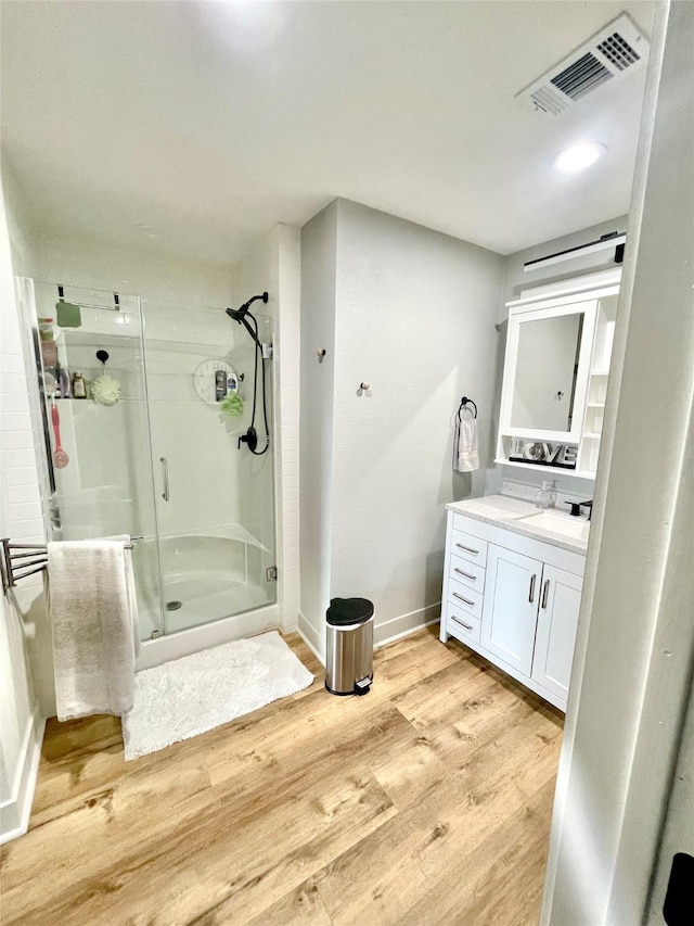 bathroom with vanity, hardwood / wood-style flooring, and a shower with door