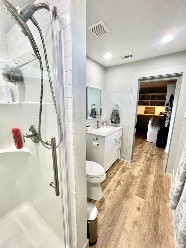 bathroom featuring vanity, hardwood / wood-style floors, toilet, and walk in shower