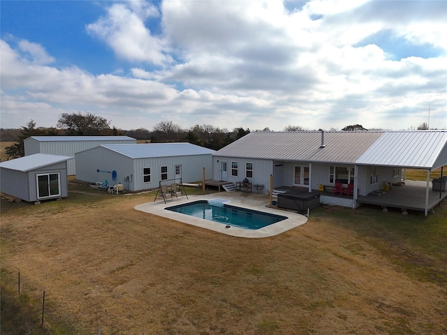 view of pool featuring an outdoor structure, a deck, a lawn, and a hot tub