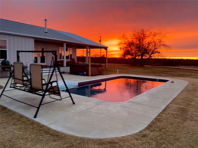 pool at dusk with a jacuzzi and a patio area