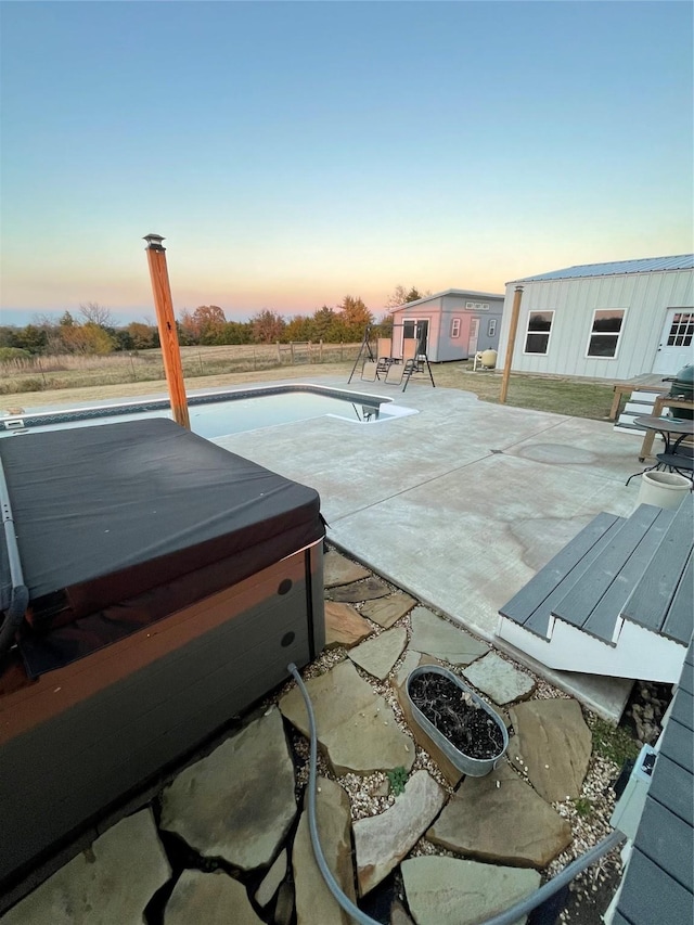 patio terrace at dusk with a pool with hot tub