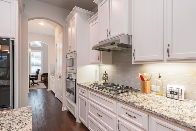 kitchen featuring dark hardwood / wood-style flooring, stainless steel appliances, white cabinetry, and light stone counters