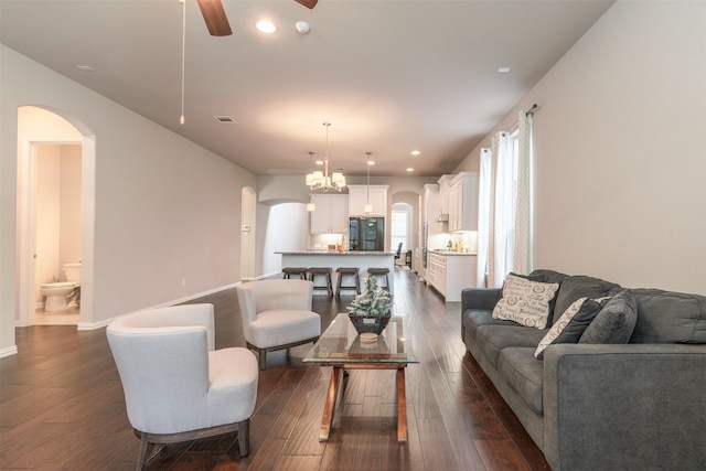 living room with ceiling fan with notable chandelier and dark wood-type flooring