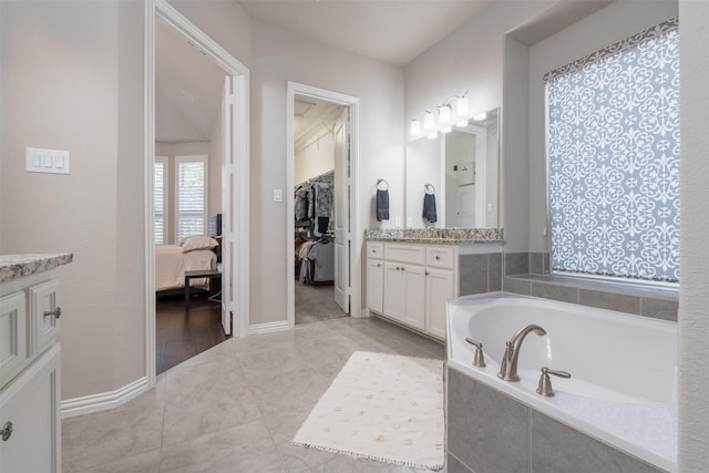 bathroom with vanity and tiled tub