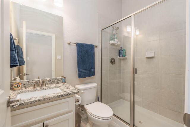 bathroom featuring vanity, toilet, and a shower with door