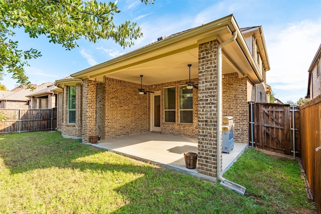 back of house featuring a lawn, ceiling fan, and a patio area