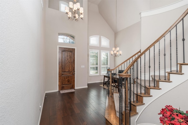 foyer entrance with dark hardwood / wood-style flooring, a towering ceiling, and a notable chandelier