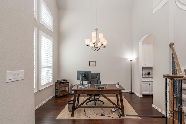 office area with dark wood-type flooring, a towering ceiling, and a healthy amount of sunlight