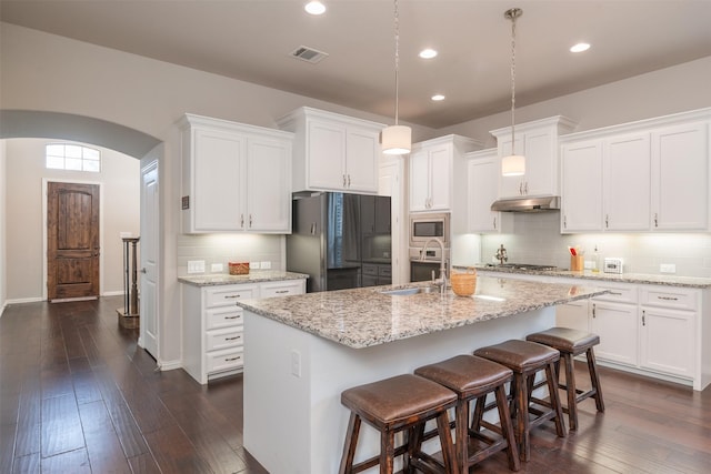 kitchen with stainless steel appliances, dark wood-type flooring, sink, a center island with sink, and white cabinetry