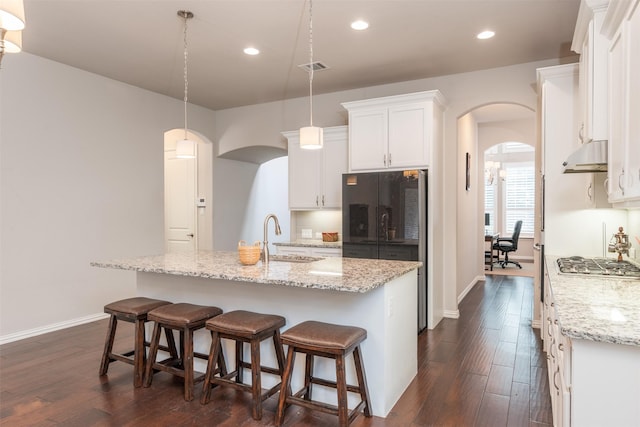 kitchen featuring a kitchen island with sink, dark wood-type flooring, sink, white cabinetry, and hanging light fixtures