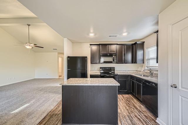 kitchen with light stone countertops, sink, dark carpet, a kitchen island, and black appliances