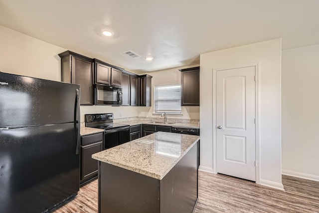 kitchen with light stone counters, sink, black appliances, light hardwood / wood-style flooring, and a kitchen island