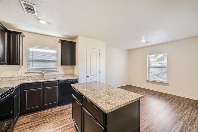 kitchen featuring a center island, black appliances, sink, light stone countertops, and wood-type flooring