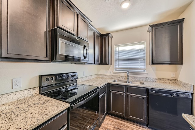 kitchen with dark brown cabinets, sink, light hardwood / wood-style flooring, and black appliances