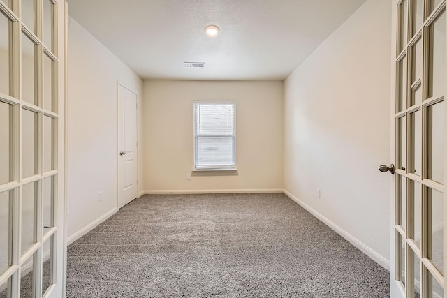 carpeted spare room featuring a textured ceiling and french doors