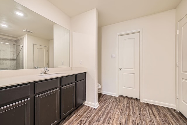 bathroom with hardwood / wood-style flooring, vanity, toilet, and walk in shower