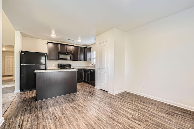 kitchen featuring dark brown cabinetry, dark wood-type flooring, a kitchen island, and black appliances