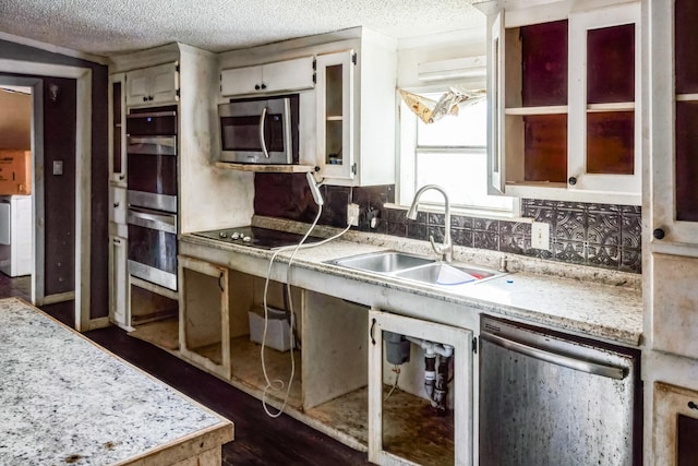 kitchen with decorative backsplash, appliances with stainless steel finishes, a textured ceiling, dark wood-type flooring, and sink