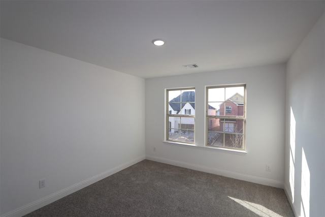 spare room with carpet flooring, visible vents, and baseboards