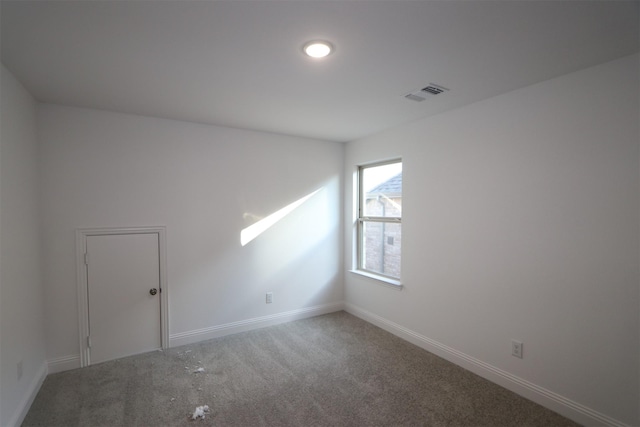 empty room with carpet floors, baseboards, and visible vents